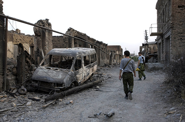 Ossetian volunteers pass a burned out van on a street in Tskhinvali.TIME